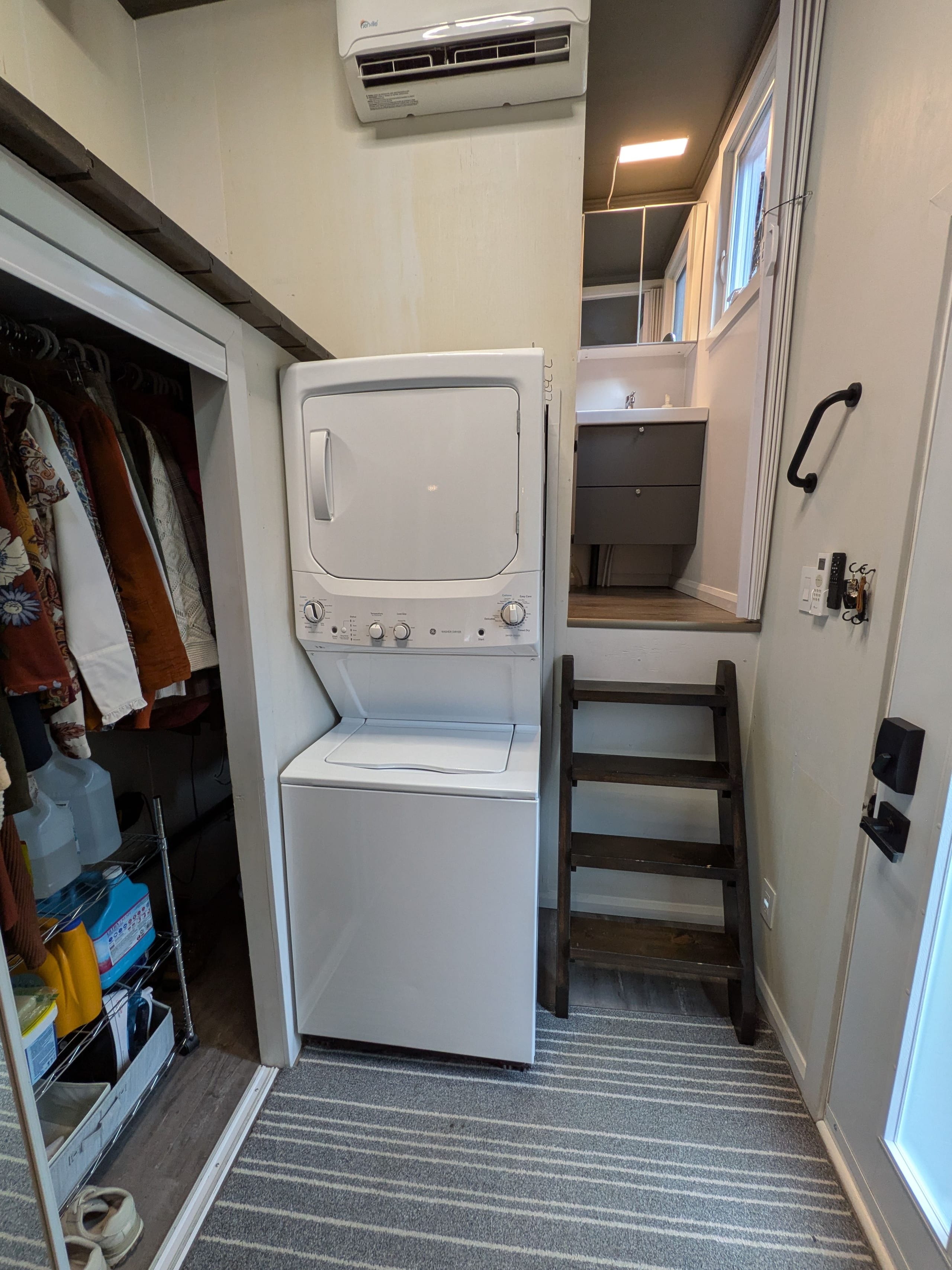Stacked washer and dryer beside the stairs and closet