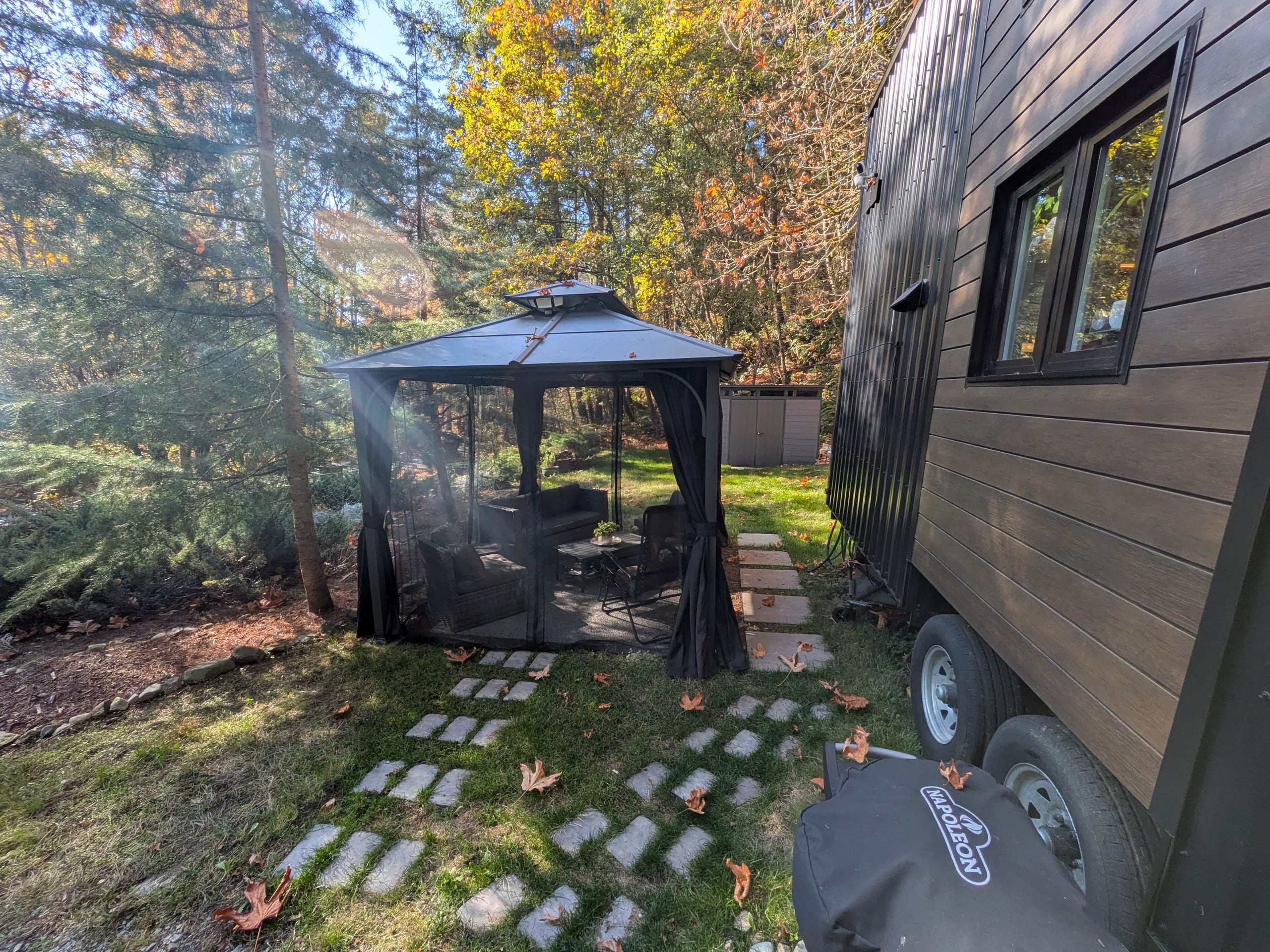 Screened gazebo beside the tiny house among autumn trees